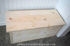 a wooden box sitting on top of carpeted floor next to a white painted wall