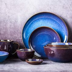 a table topped with lots of blue dishes next to a gray wall and white walls