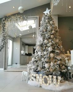 a decorated christmas tree in front of a mirror with the word snow written below it