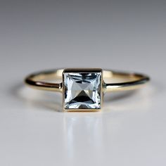 "This beautiful aquamarine ring was made of 5*5 mm princess cut square aquamarine stone in 14k gold bezel setting and 14k yellow gold 1.3mm band. It's perfect for wearing alone or mixing and matching with your other rings. DETAILS  Ring Band: 14K YELLOW GOLD Ring Band size: 1.3mm wide (thick) Gemstone: Natural Aquamarine Gemstone size and cut: 5X5mm princess cut Aquamarine is March birthstone. Aquamarine is the anniversary gemstone (especially for the 16th and 19th year of marriage) and March bi Ring Square Stone, March Birthstone, March Birthstone Ring, Bezel Engagement Ring, Jewellery Sketches, Gold Ring Designs, Birthstone, Detailed Ring, Aquamarine Stone