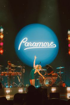 a woman standing on top of a stage with her arms in the air