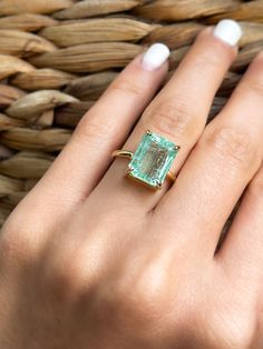 a woman's hand with a ring on it and an emerald stone in the middle