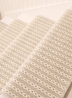 two pieces of white knitted material on the floor next to each other with dots