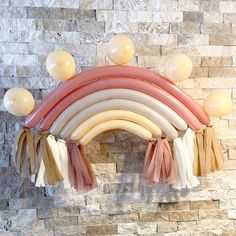 balloons and tassels are hanging on the wall in front of a brick wall