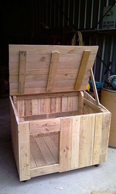 a large wooden box sitting on top of a cement floor next to a metal container