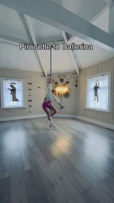 a woman is doing aerial acrobatics in an empty room with two windows