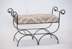 a wrought iron bench with a patterned seat cover on it's backrest and foot rest