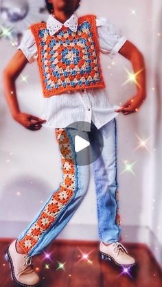 a young boy is standing in front of a white wall wearing an orange and blue crochet vest