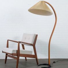 a chair and lamp in front of a white brick wall with a floor lamp next to it