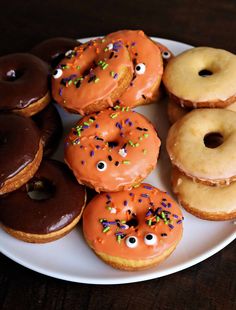 a white plate topped with donuts covered in frosting and sprinkles