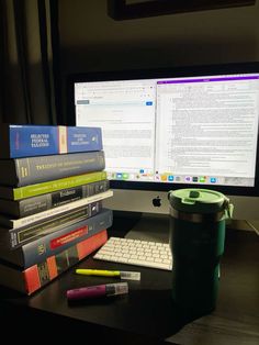 a stack of books sitting on top of a desk next to a computer monitor and keyboard