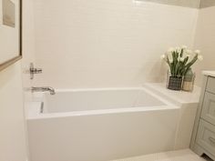 a white bath tub sitting next to a sink in a bathroom on top of a tiled floor