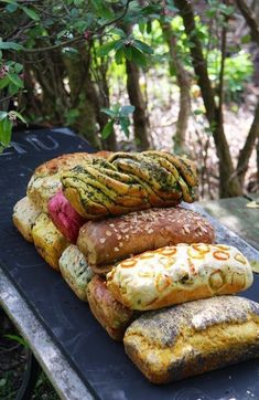 a pile of bread sitting on top of a picnic table next to trees and bushes