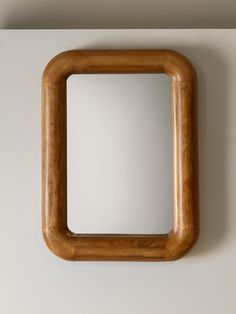 a square wooden mirror hanging on the wall