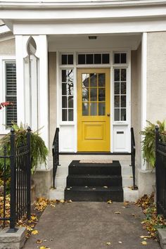 a yellow front door on a white house