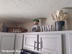 kitchen cabinets with utensils on top of them and wooden signs above the stove