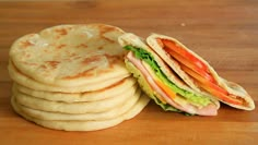 a stack of tortilla sandwiches sitting on top of a wooden table