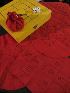 a yellow box sitting on top of a red cloth covered floor next to two dice boards