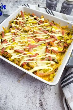 a casserole dish with bacon and cheese on top, next to two bottles of soda