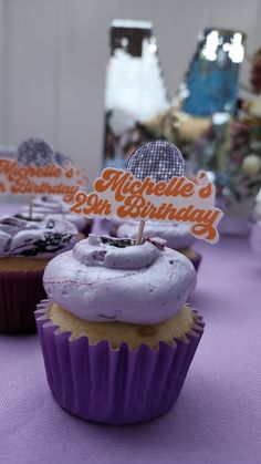 purple cupcakes with white frosting and an orange happy birthday sign