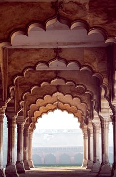 an archway in the middle of a building with columns and arches on either side, looking out over a large body of water