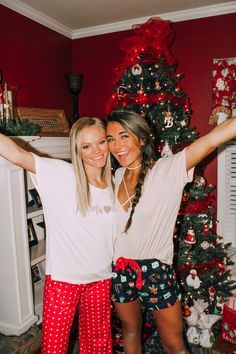 two women standing in front of a christmas tree