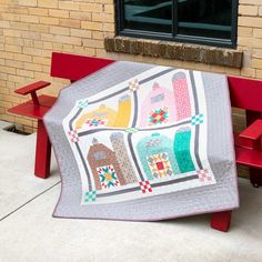 a quilted blanket sitting on top of a red bench next to a brick building