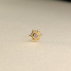 a gold ring with a small diamond in the center on a white surface, close up