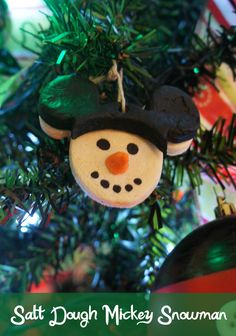 a snowman ornament hanging from a christmas tree with the words salt dough mickey snowman on it