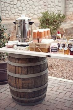 a table with some food on top of it next to a barrel and potted plants