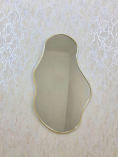 a mirror that is on the wall in front of a white wall with gold trim