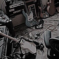 an assortment of guitars and amps are on the floor