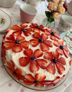 a cake with strawberries and blueberries on it sitting on top of a table