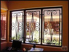 an office area with a desk, computer and window that has wrought iron work on it