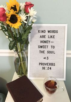 a vase filled with flowers next to a sign that says kind words are like honey to the soul