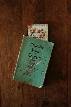 an old book with writing on it sitting on top of a wooden floor next to a pair of scissors