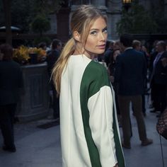 a woman standing in front of a crowd wearing a green and white top with long sleeves