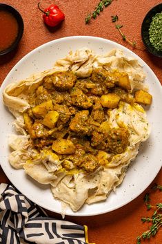 a white plate topped with food next to bowls of sauce and seasoning on a table