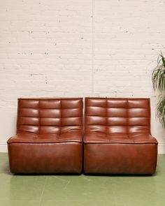 two brown leather couches sitting next to each other