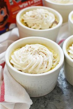 four white bowls filled with food sitting on top of a marble counter next to a red and white napkin