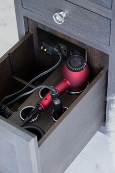 an open drawer with hair dryer and other items in it