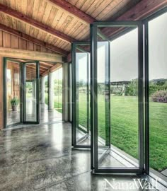 an empty room with glass doors and grass in the backround, looking out onto a large open field