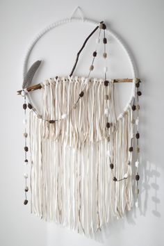 a white wall hanging with beads and feathers