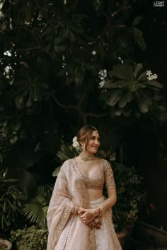 a woman in a pink lehenga standing next to some plants