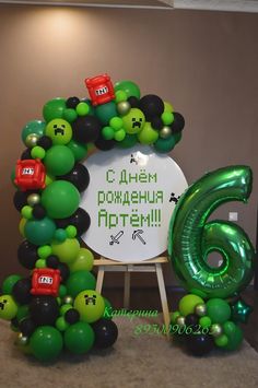 the balloon arch is decorated with green, black and red balloons that spell out 6