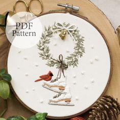 a cross stitch pattern with a cardinal on a sled and pine cones in the background