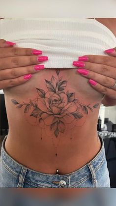 a woman's stomach with pink nails and tattoos on her belly, showing the flower tattoo