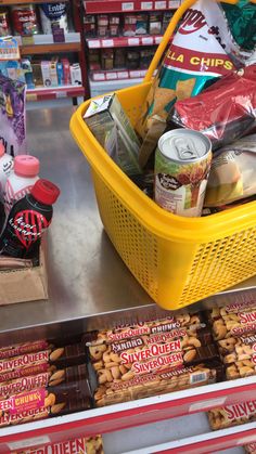 a yellow basket filled with snacks sitting on top of a metal counter in a store