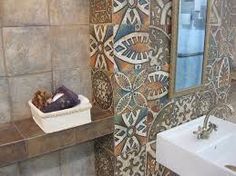 a bathroom with a sink, mirror and tiled walls