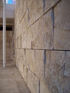 there is a wall made out of stone blocks in the hallway with tile flooring